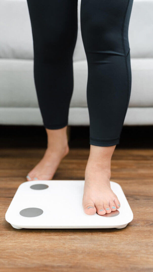 Woman Leg Stepping On Scales At Home. Measurement Instrument In Kilogram For Diet Lose Weight Concept